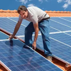 Instalacja PV na dachu: mężczyzna montuje panele słoneczne.