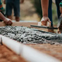 Pracownicy wygładzają świeży beton. Zastanawiasz się, ile kosztuje m3 betonu na budowie?