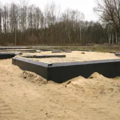 Fundament domu w piasku, otoczony czarną folią. To dopiero początek budowy, przyszły dom otacza opaska wokół domu.