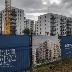 Budowa osiedla mieszkaniowego w Gdańsku, widoczne dźwigi i banery deweloperskie.