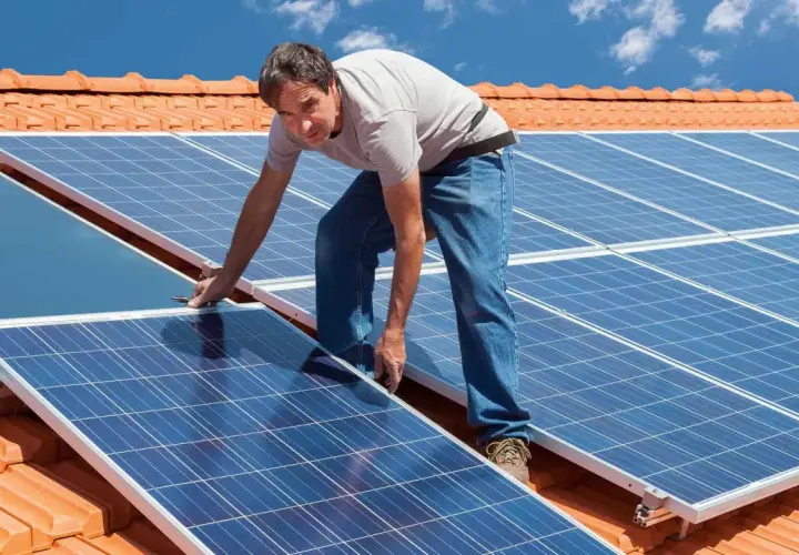 Instalacja PV na dachu: mężczyzna montuje panele słoneczne.
