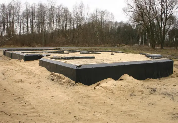 Fundament domu w piasku, otoczony czarną folią. To dopiero początek budowy, przyszły dom otacza opaska wokół domu.
