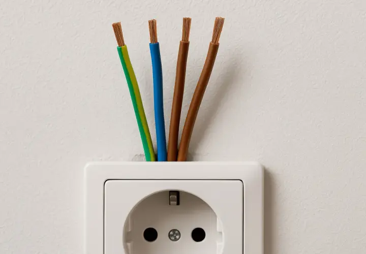 Cztery przewody elektryczne wychodzące z białego gniazdka. Zastanawiasz się, jaki kabel do gniazdek?