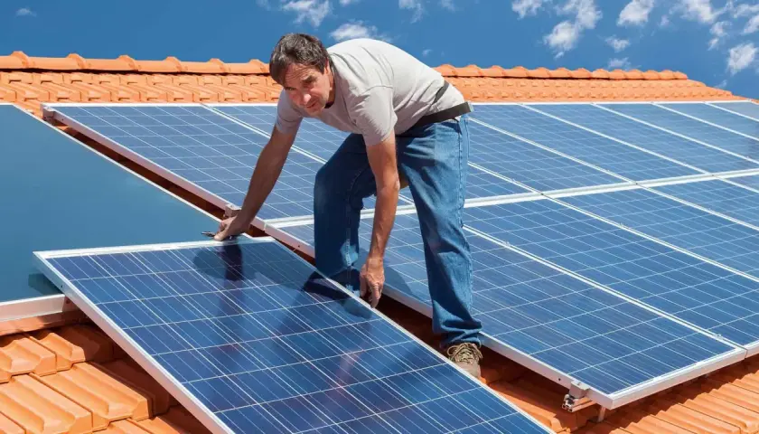 Instalacja PV na dachu: mężczyzna montuje panele słoneczne.