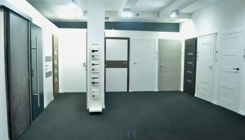 Salon z drzwiami i oknami, prezentujący różne modele drzwi wewnętrznych i zewnętrznych.