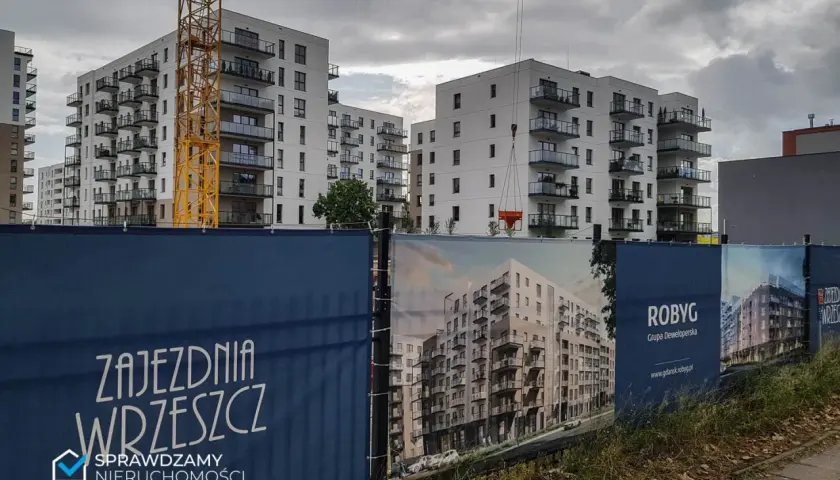 Budowa osiedla mieszkaniowego w Gdańsku, widoczne dźwigi i banery deweloperskie.
