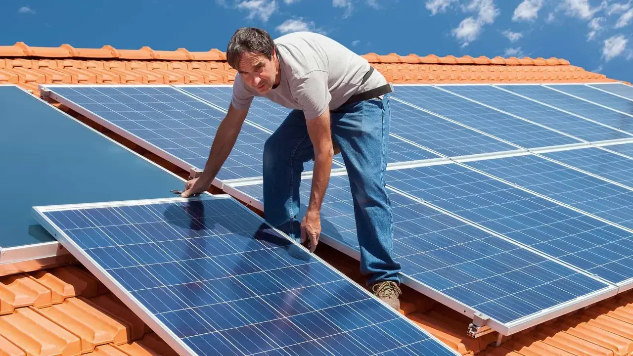 Instalacja PV na dachu: mężczyzna montuje panele słoneczne.