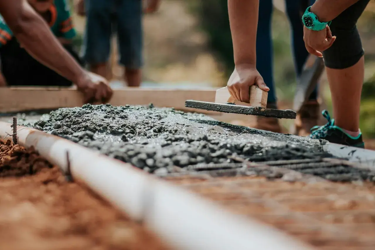 Pracownicy wygładzają świeży beton. Zastanawiasz się, ile kosztuje m3 betonu na budowie?